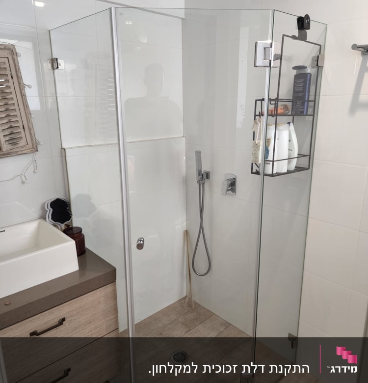 מקלחון זכוכית עם ראש מקלחת ומדף מוצרי טיפוח